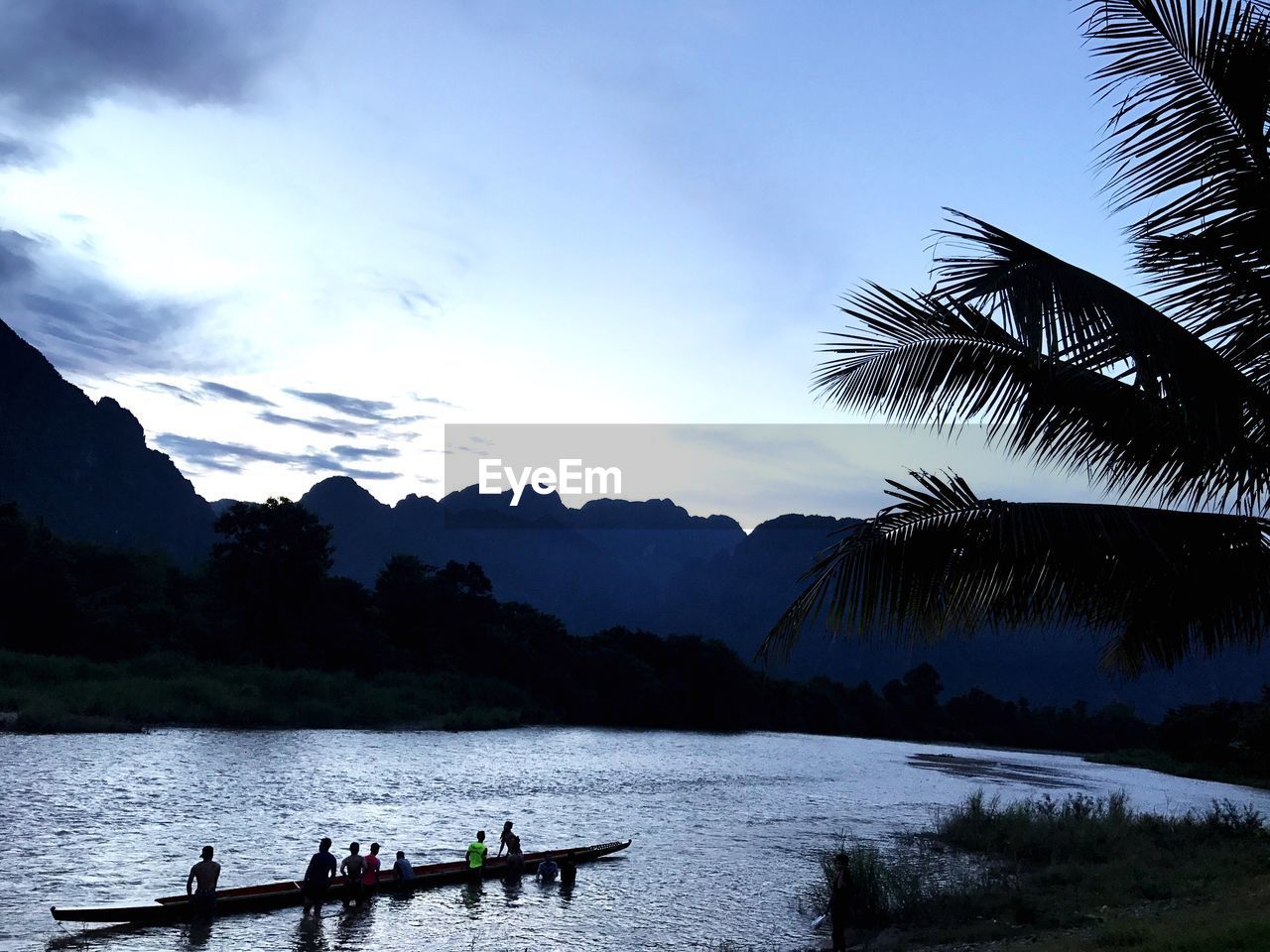 People in boat on lake against sky