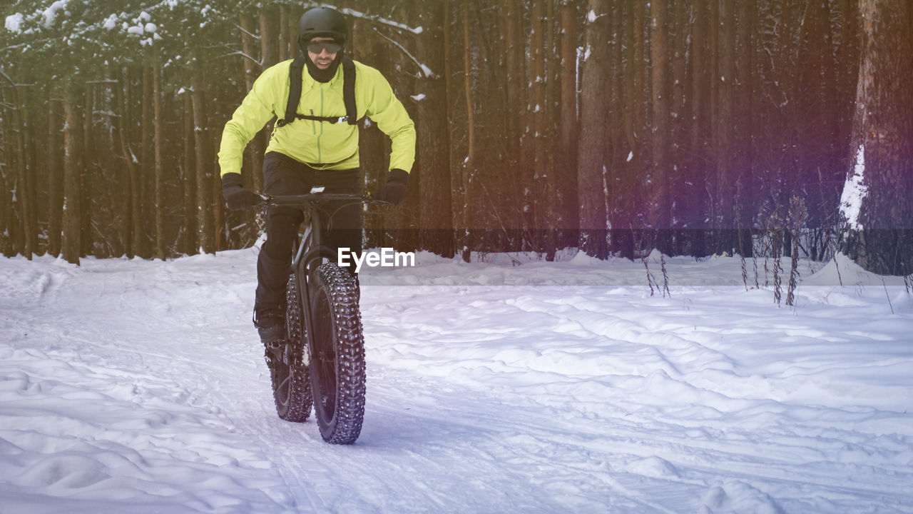 Man riding bicycle on snow covered field