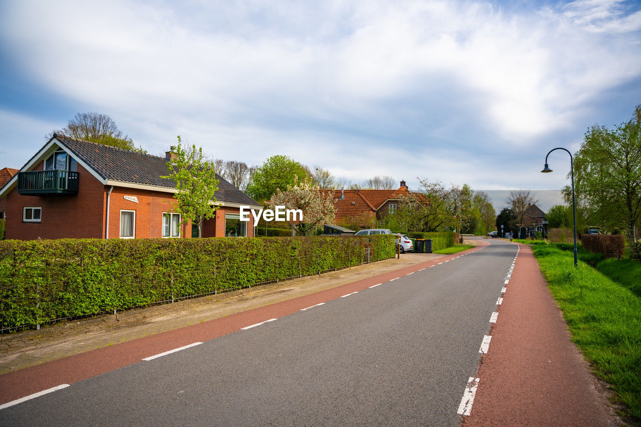 empty road by trees against sky