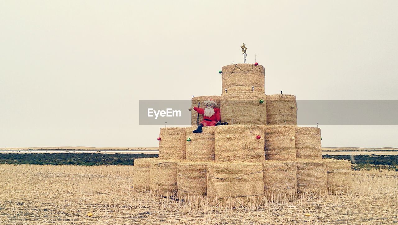 Santa claus on hay bales against sky
