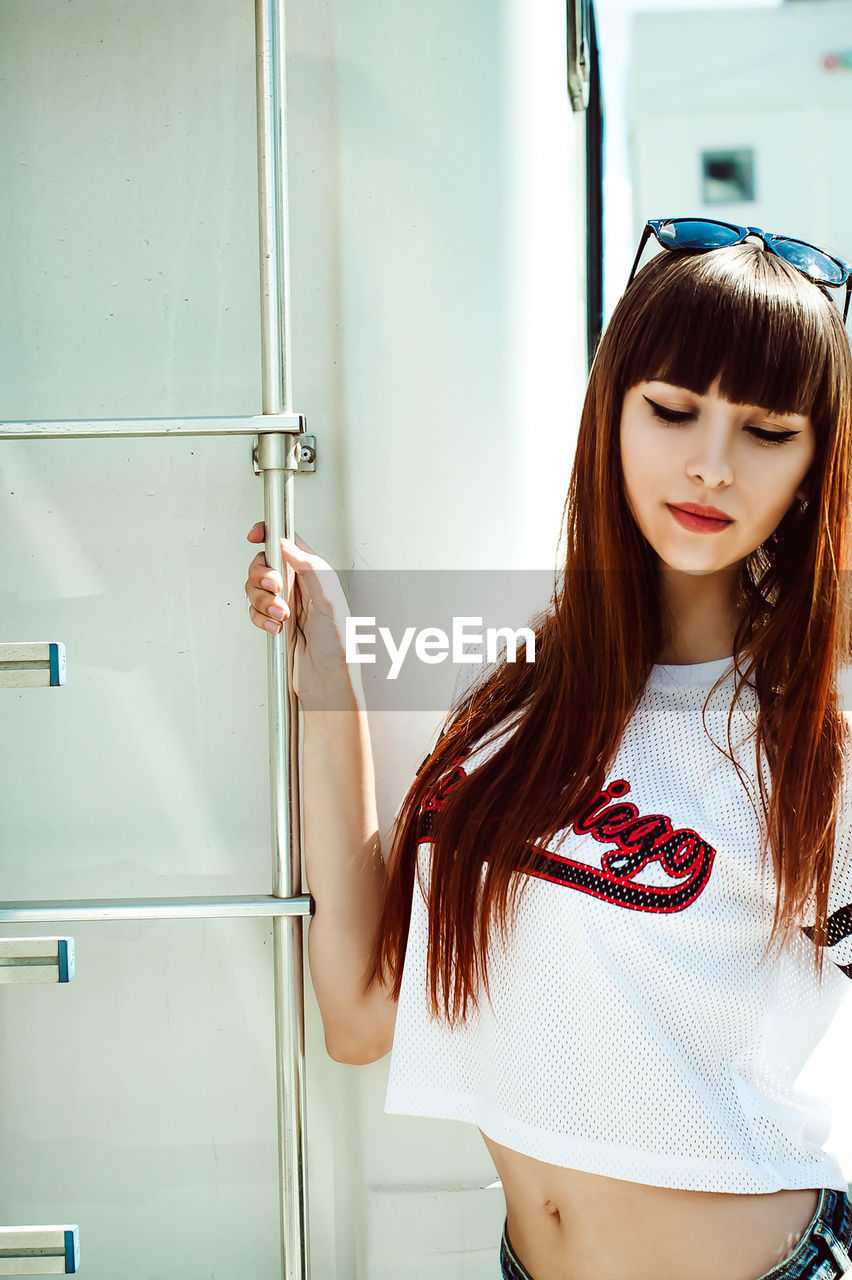 Young woman standing by camper trailer