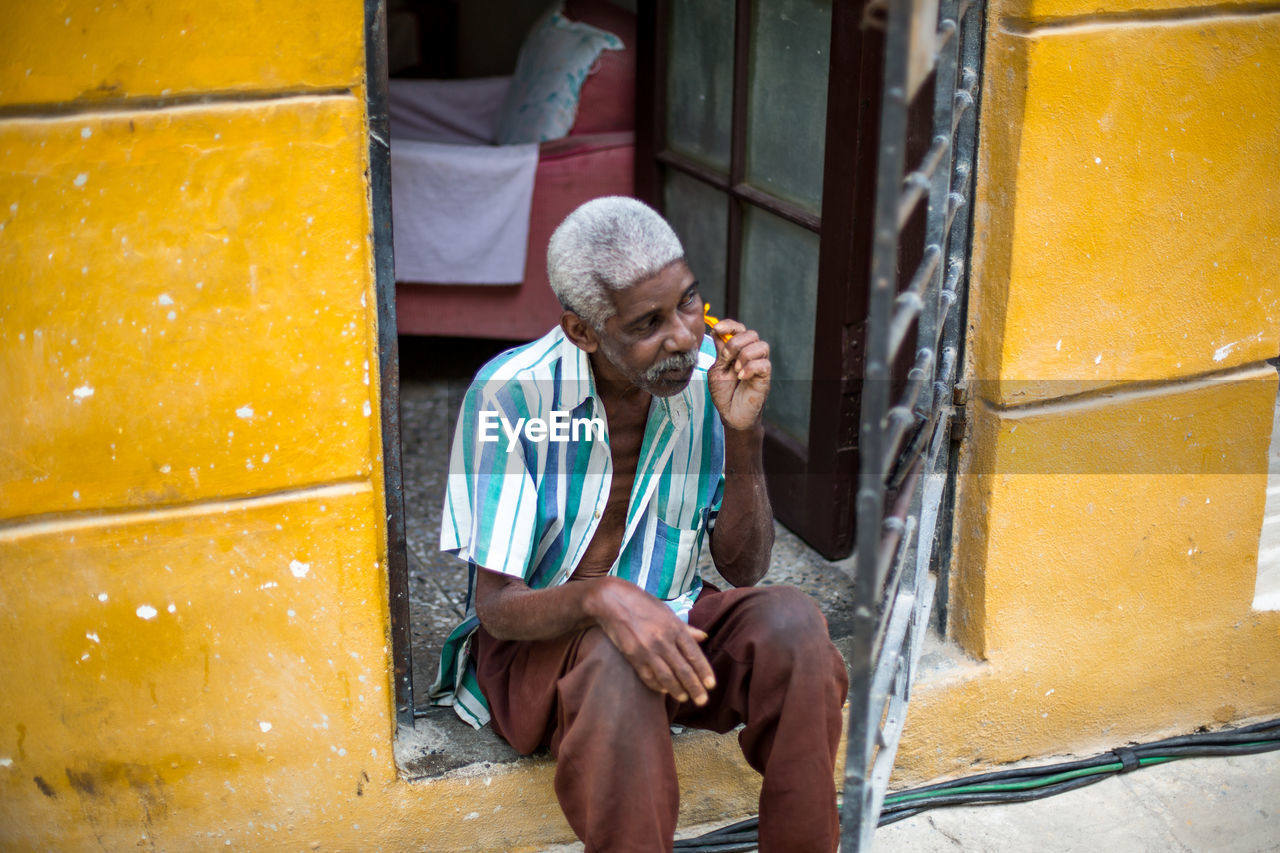 MAN USING MOBILE PHONE WHILE SITTING IN CITY