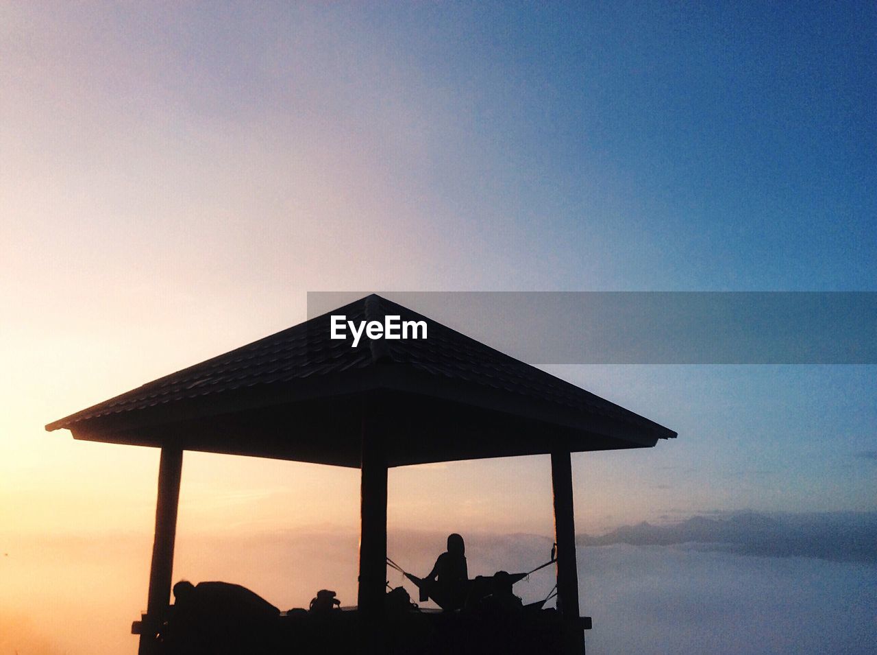 Silhouette woman in gazebo against sky during sunrise