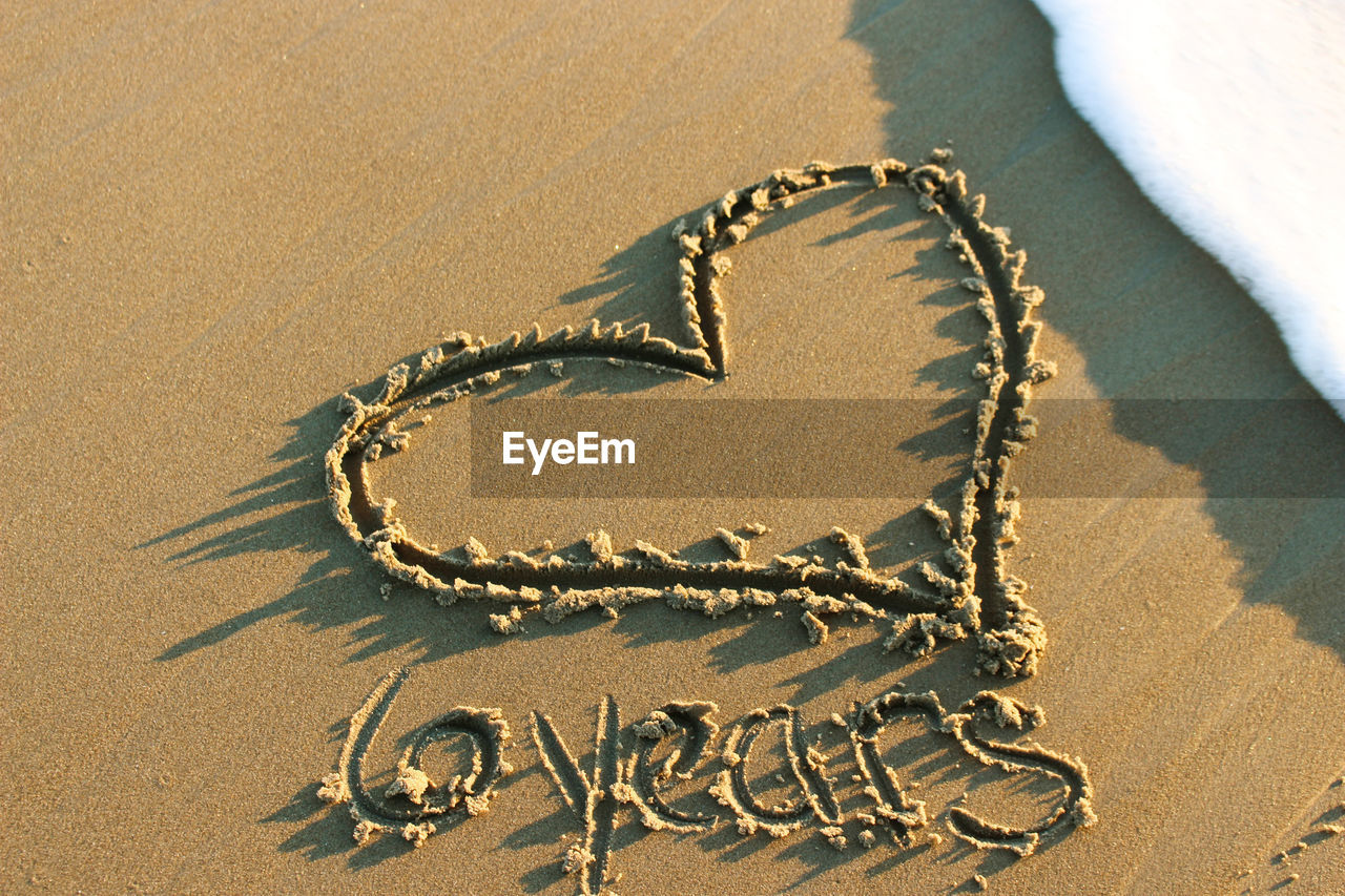 Close-up of heart shape on sand at beach