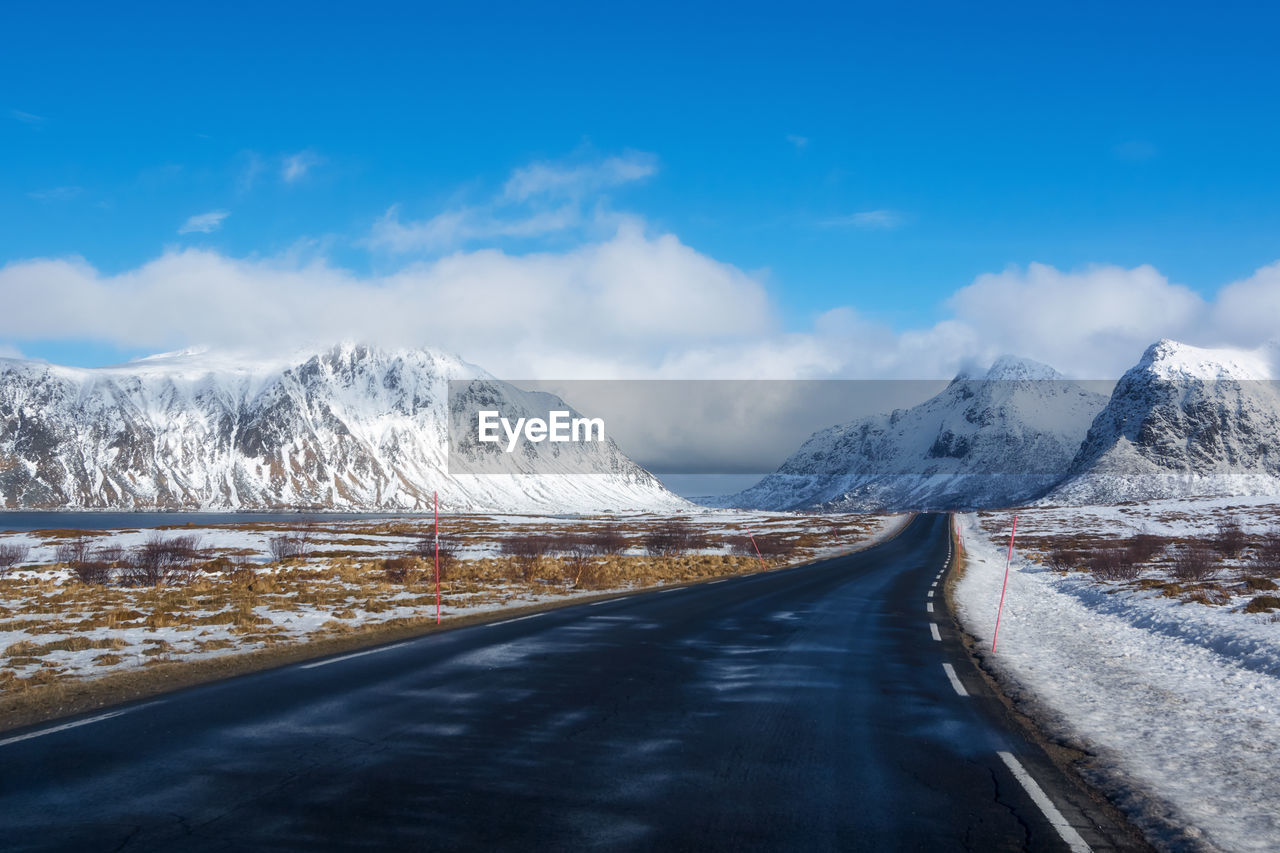 Road amidst snowcapped mountains against sky during winter norway