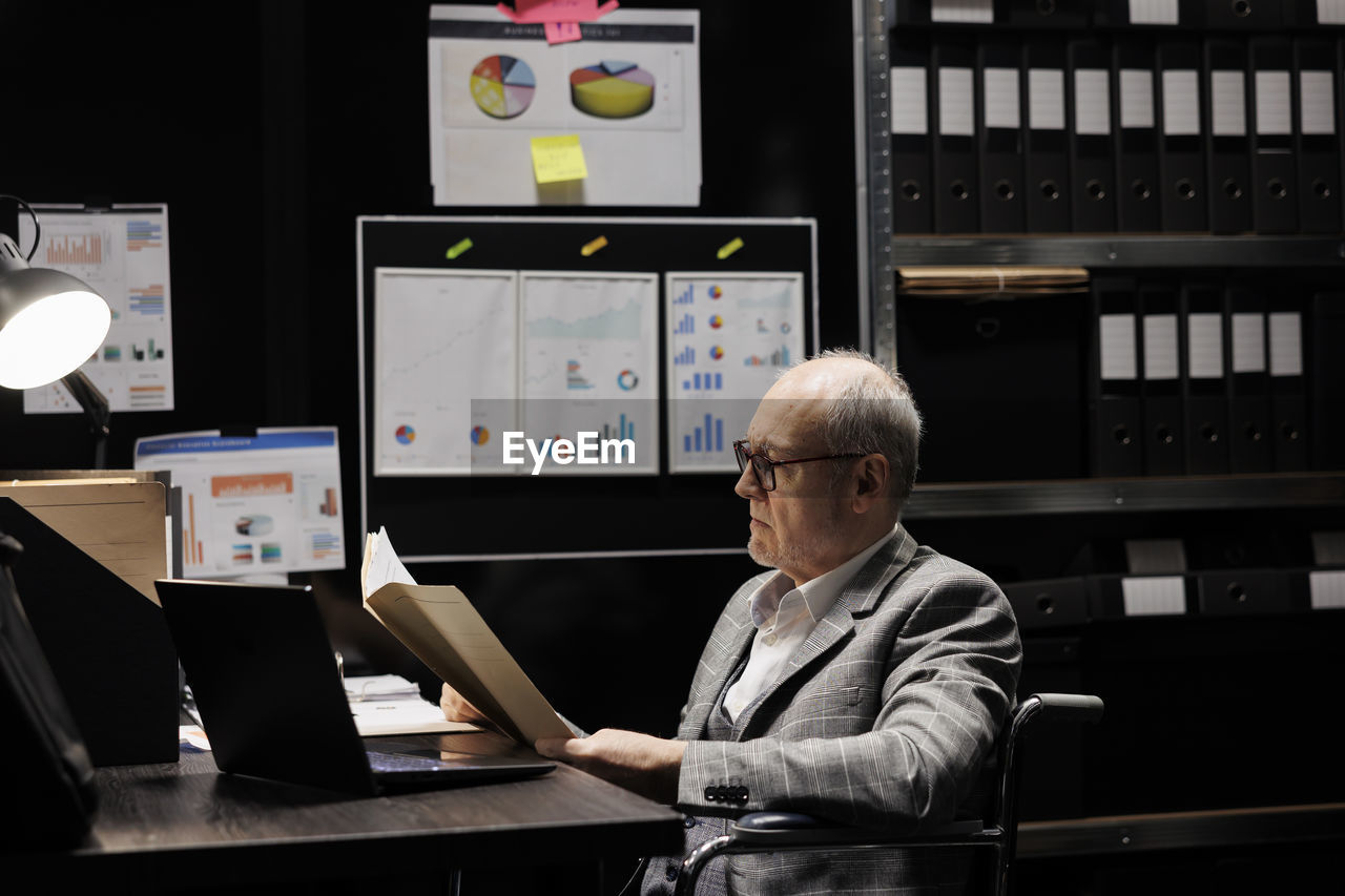 rear view of man using digital tablet while sitting in office