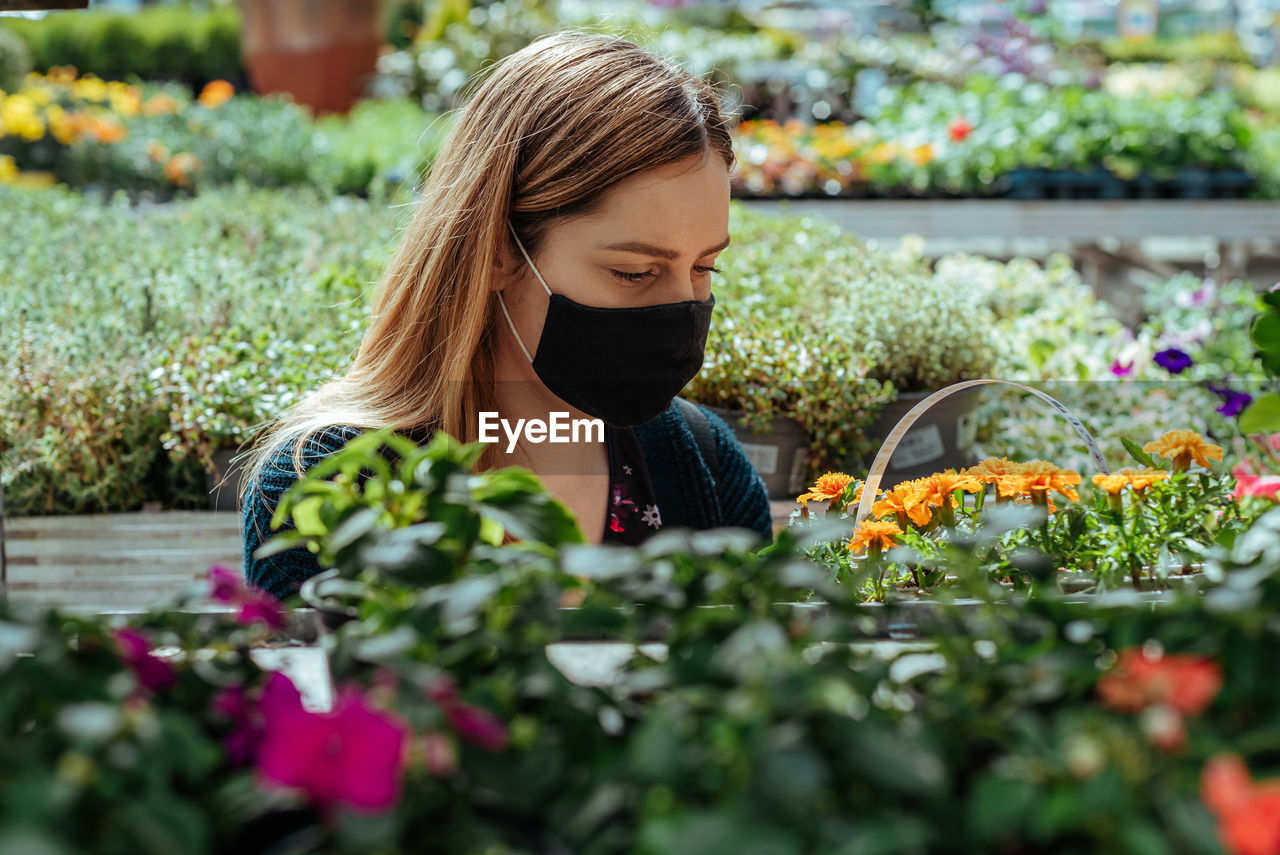 Woman with face mask in greenhouse buying flowers