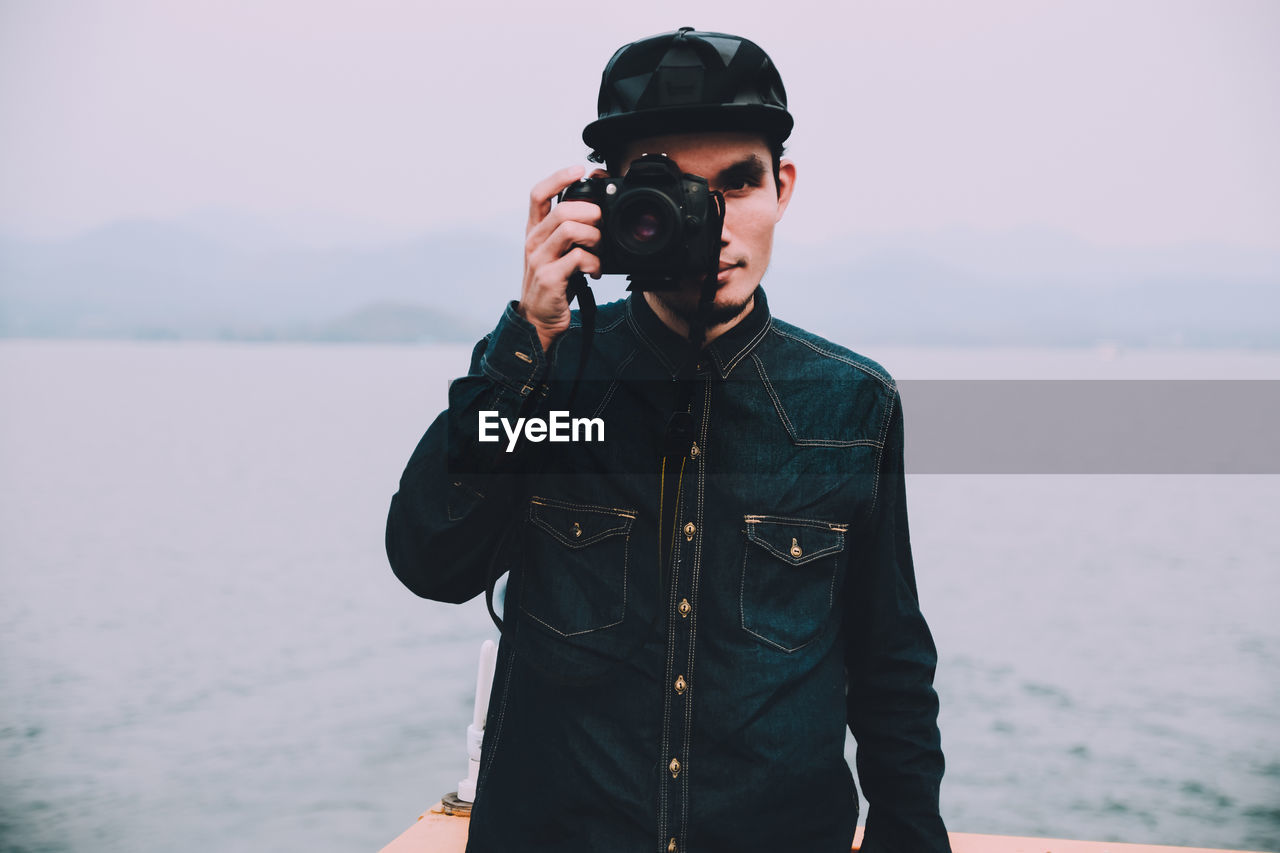 Man photographing with camera against sky