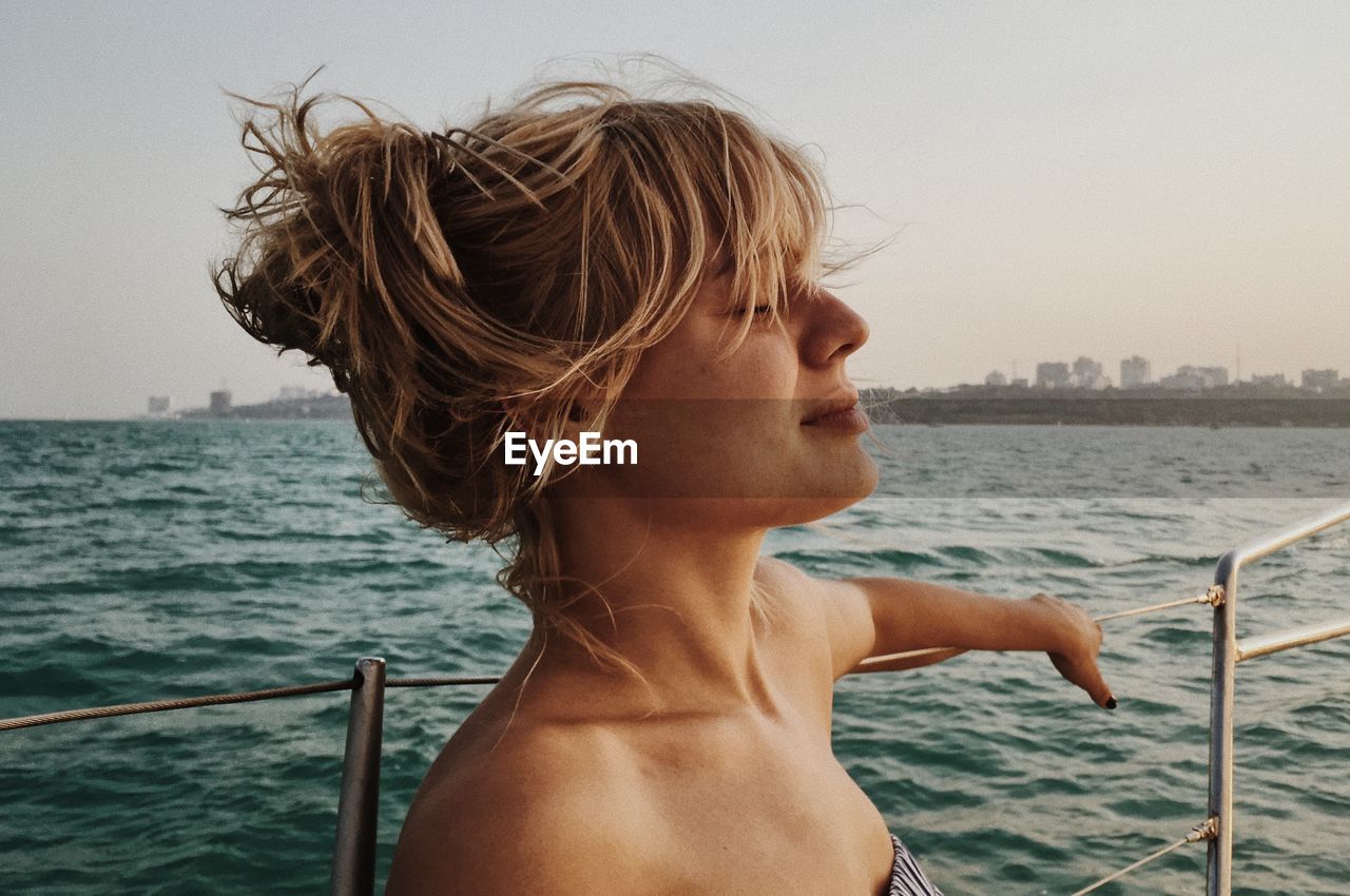 Close-up of young woman on boat in sea during sunset