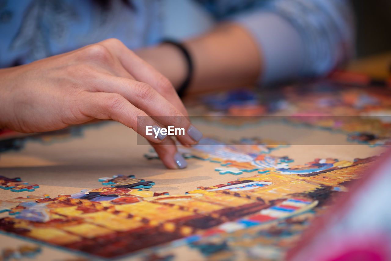 Midsection of woman playing jigsaw puzzle on table