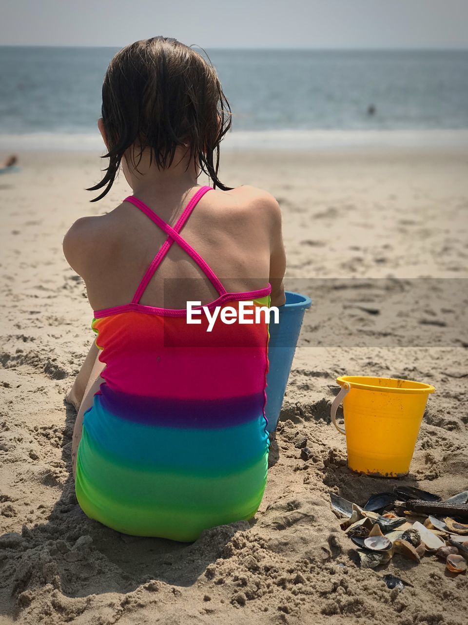 Rear view of girl playing on sand at beach during summer