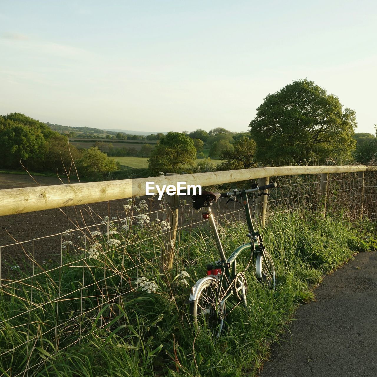 Bicycle parked amidst railing and street against sky