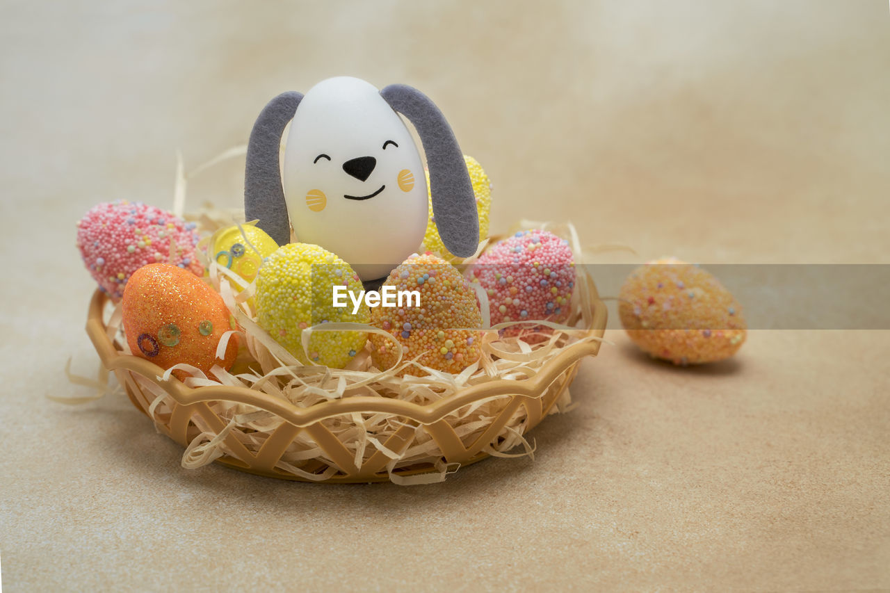 Nest basket with colorful easter eggs and eggshell figurine, creative craft with kids