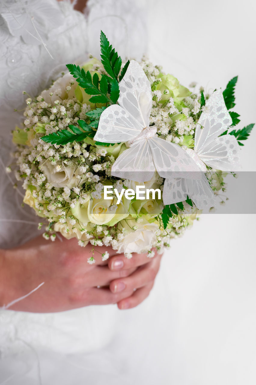 Midsection of bride holding butterflies on bouquet