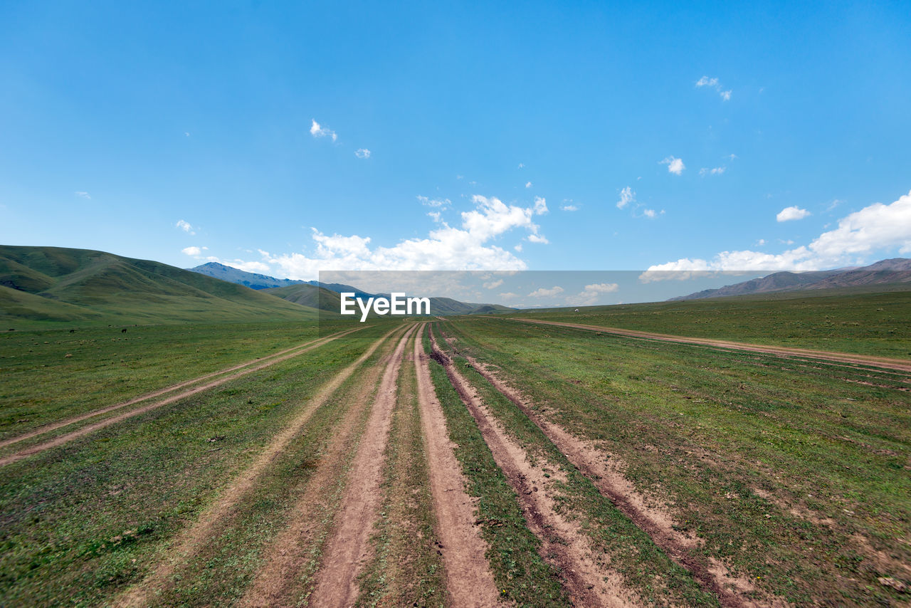 Panoramic view of road amidst field against sky