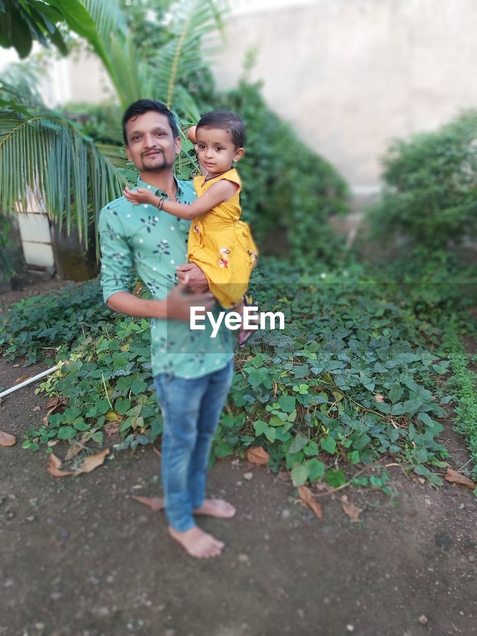 Full length of man standing with daughter by plant