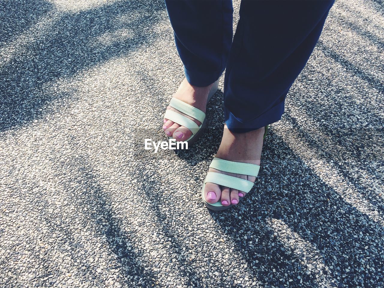 Low section of woman wearing sandals standing on road