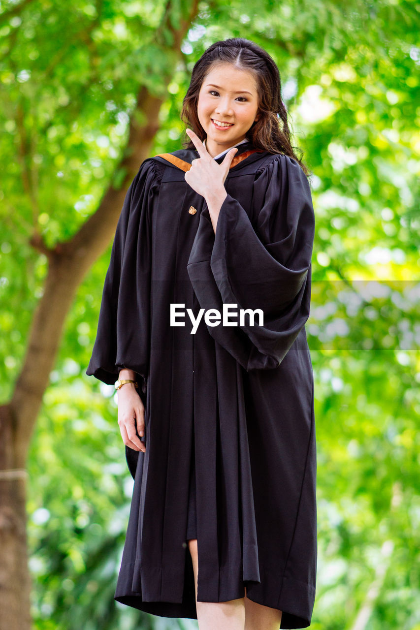 Portrait of young woman standing against trees