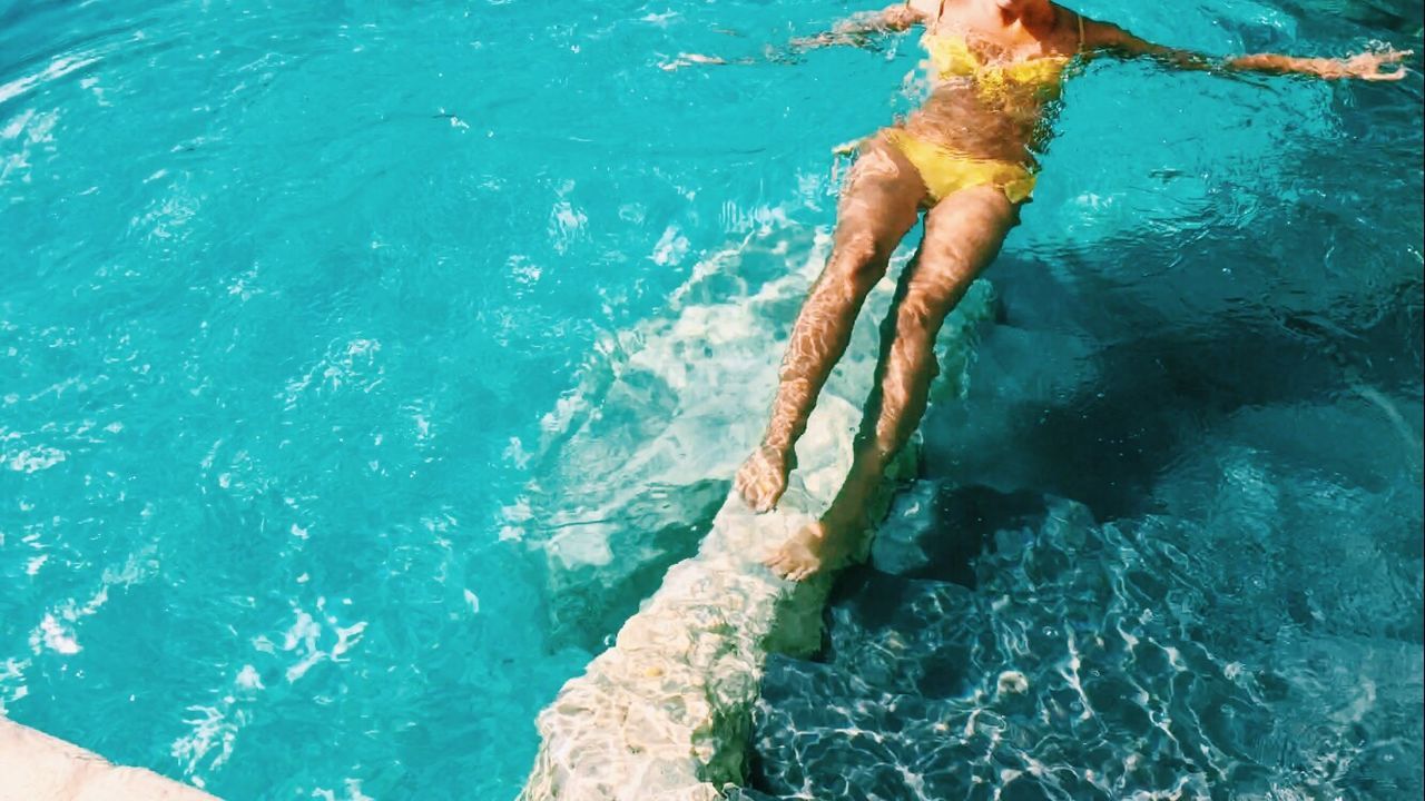 HIGH ANGLE VIEW OF PERSON SWIMMING IN POOL