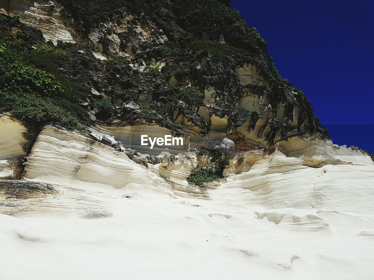 Low angle view of mountain against clear blue sky during sunny day