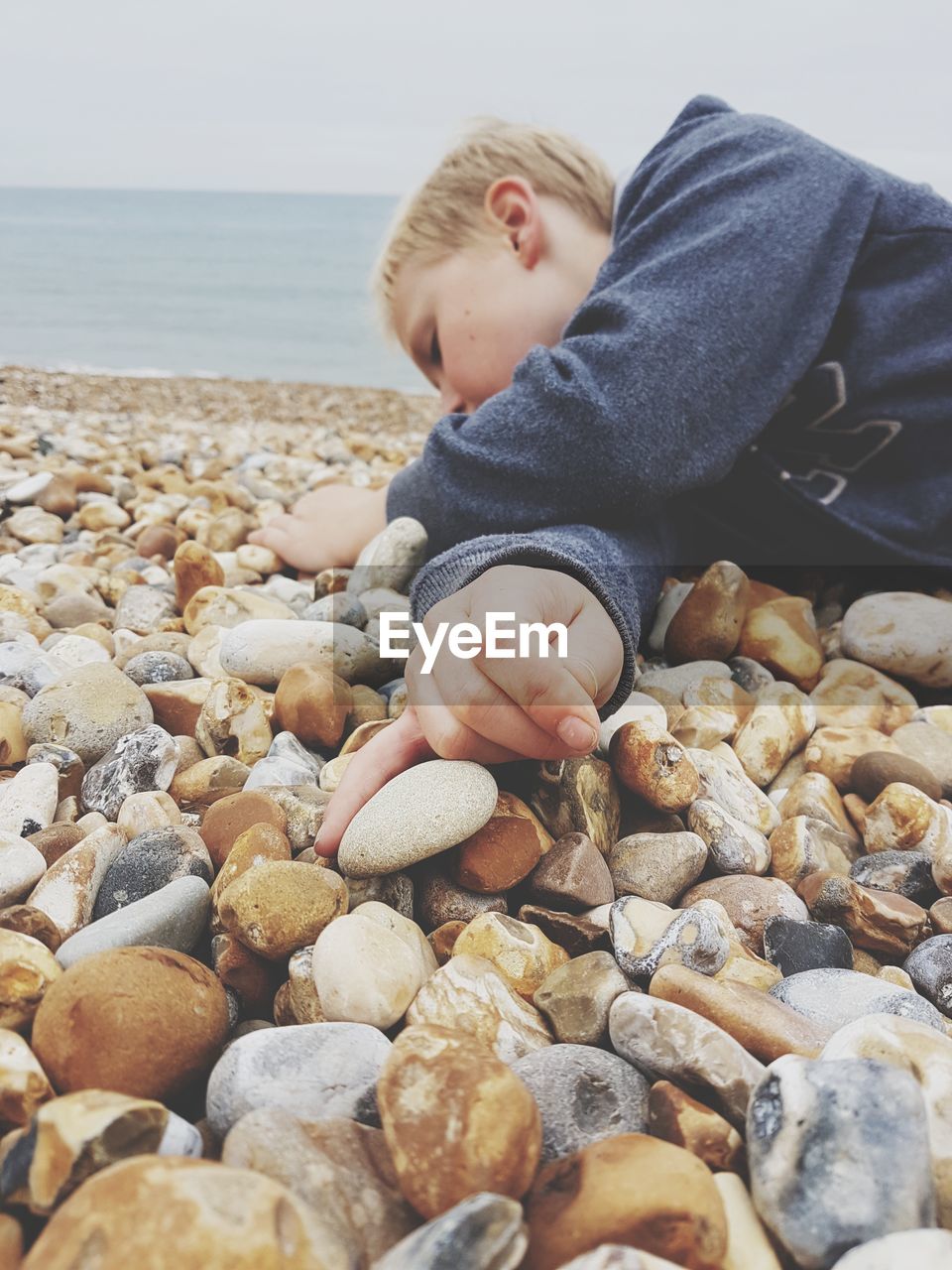 Boy lying down on pebbles at beach