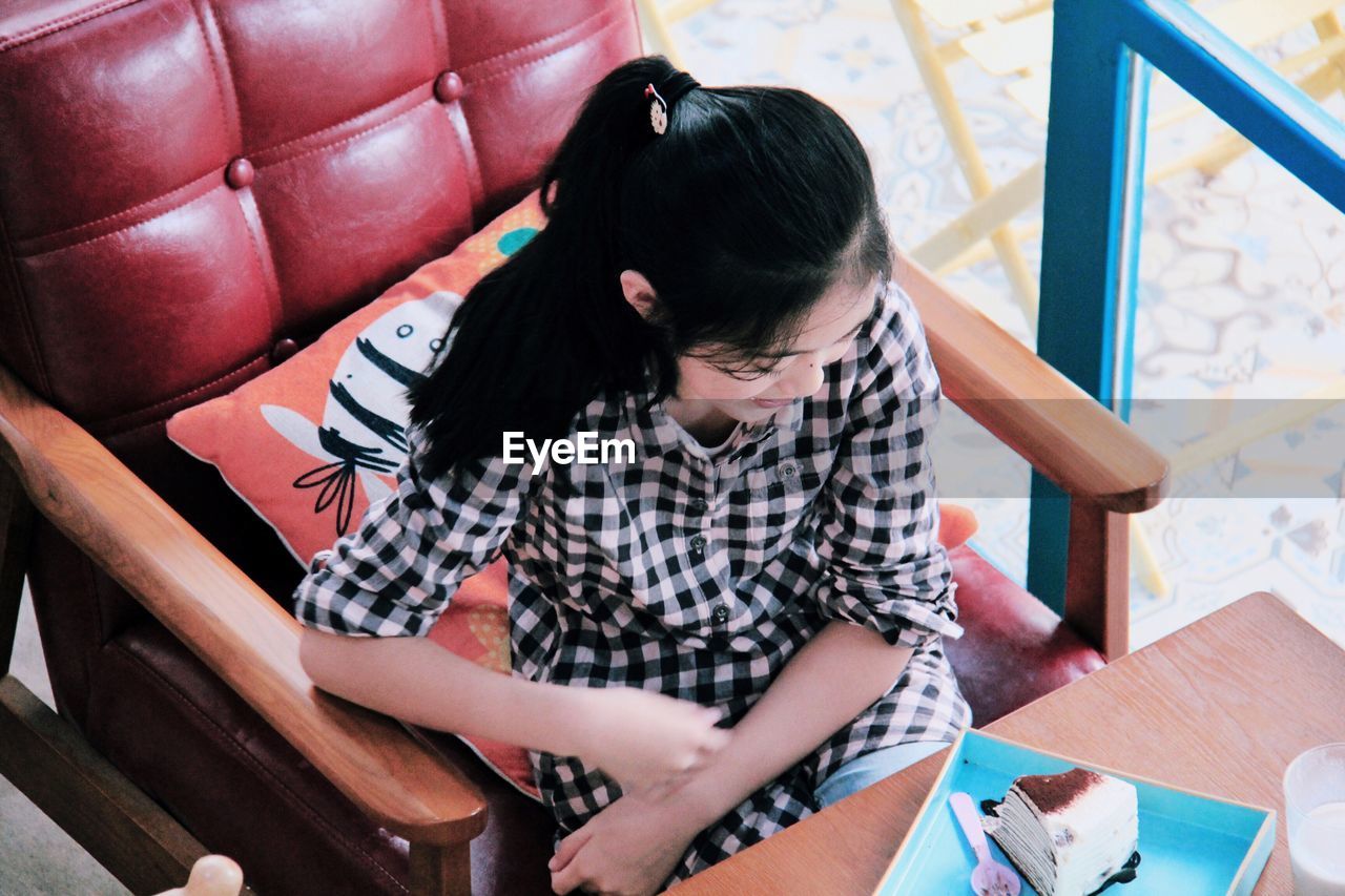 High angle view of girl with cake slice sitting in restaurant