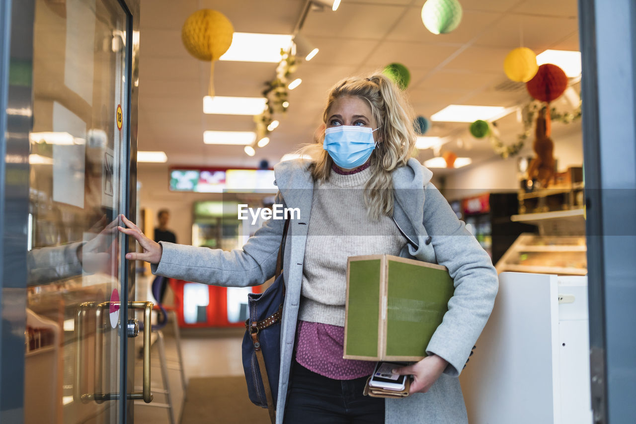 Female customer carrying package while leaving store during covid-19