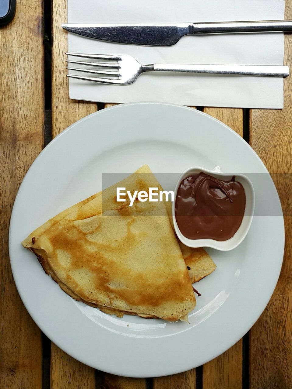 High angle view of crepe and chocolate sauce on table