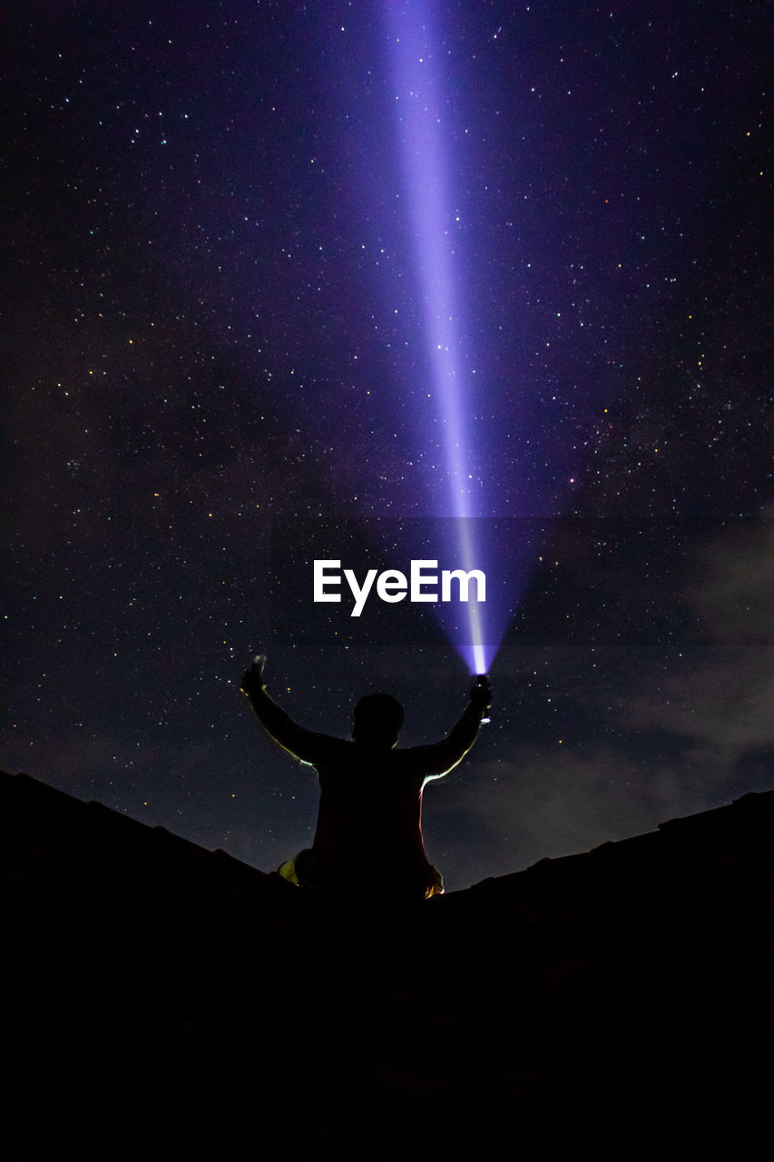 SILHOUETTE MAN STANDING AGAINST STAR FIELD AT NIGHT