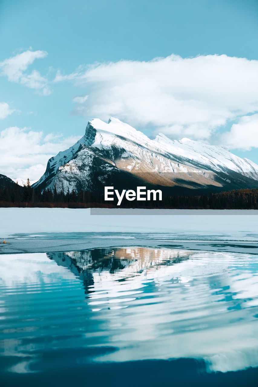 Scenic view of lake by snowcapped mountain against sky