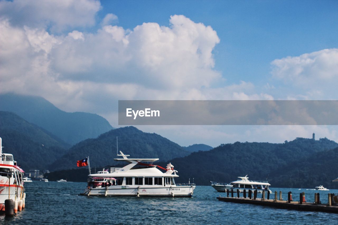 BOATS IN SEA AGAINST MOUNTAINS