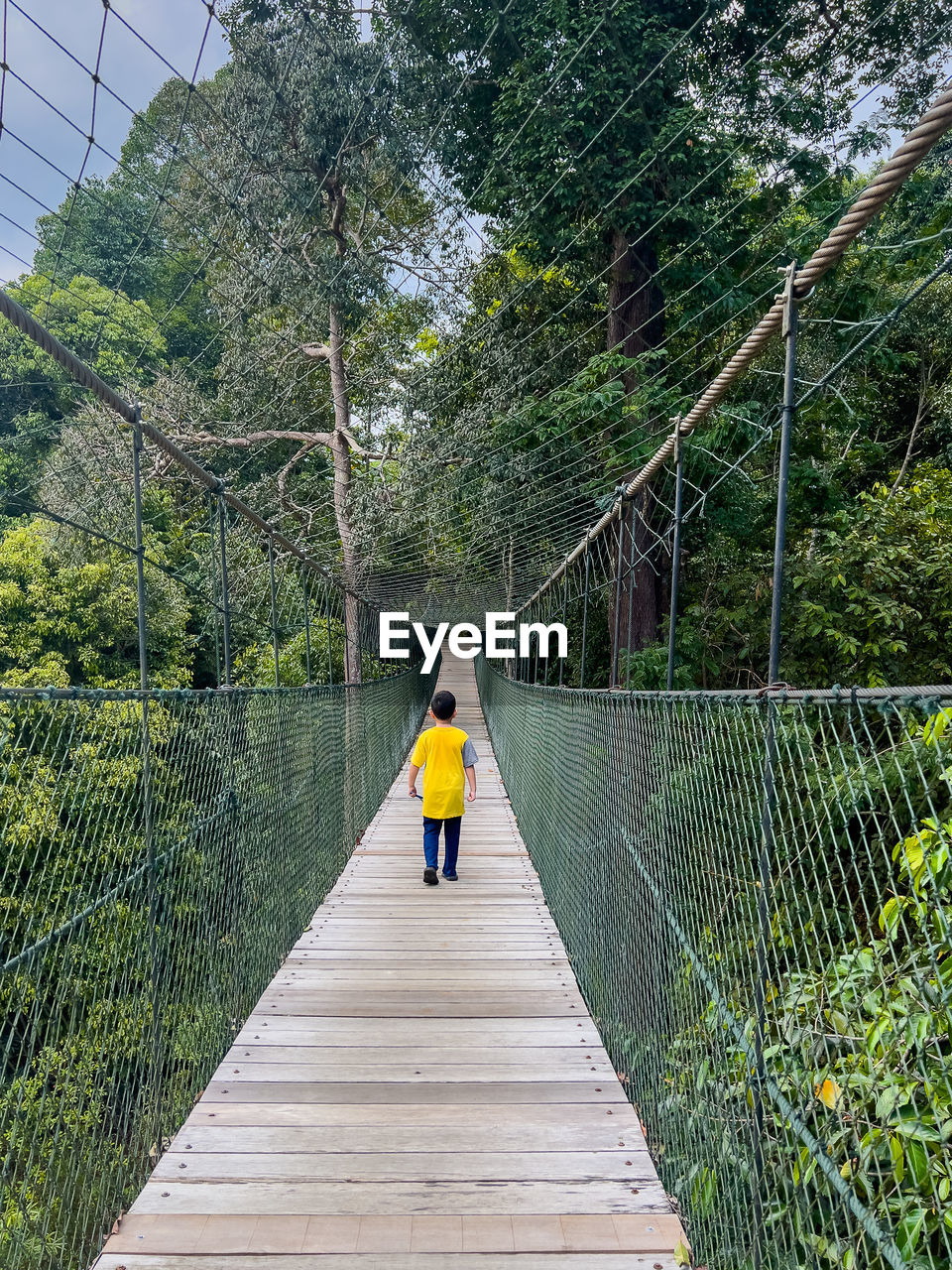 Rear view of boy walking on footbridge