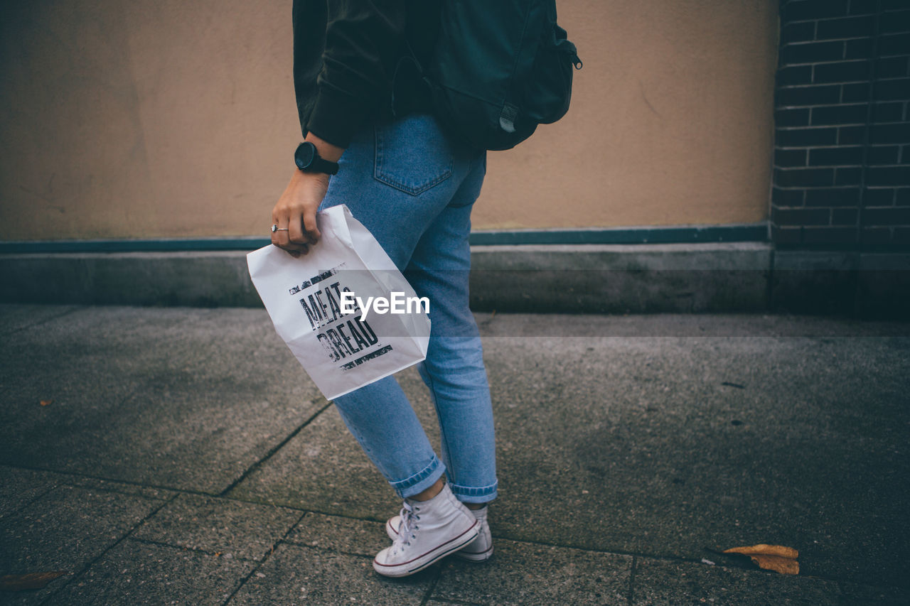 LOW SECTION OF MAN STANDING ON SIDEWALK WITH TEXT