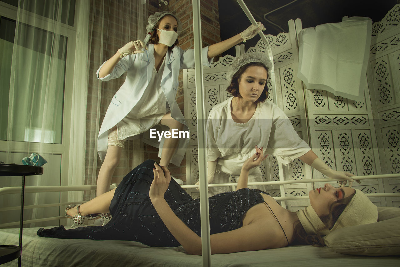 Female doctor and nurse with patient lying on bed at hospital