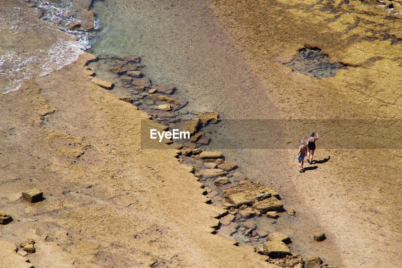 High angle view of couple walking on shore