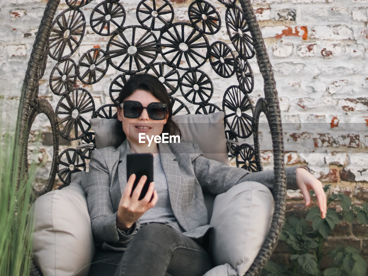 A young beautiful caucasian girl holds a phone in her hands and looks at the smartphone screen