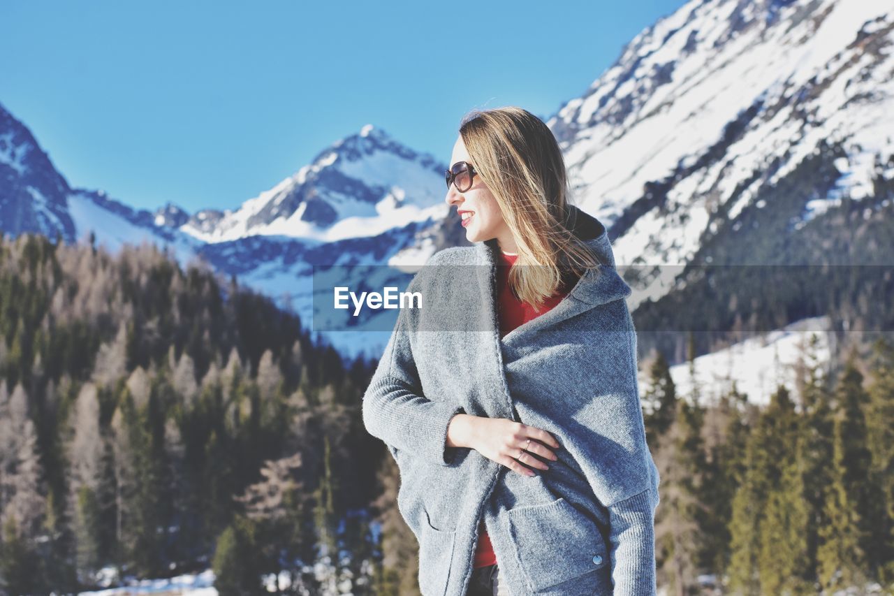 Woman standing against snow capped mountain