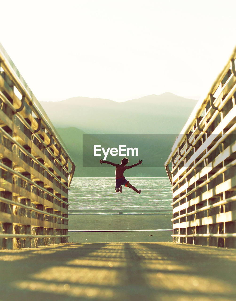 Rear view of boy jumping at beach against clear sky