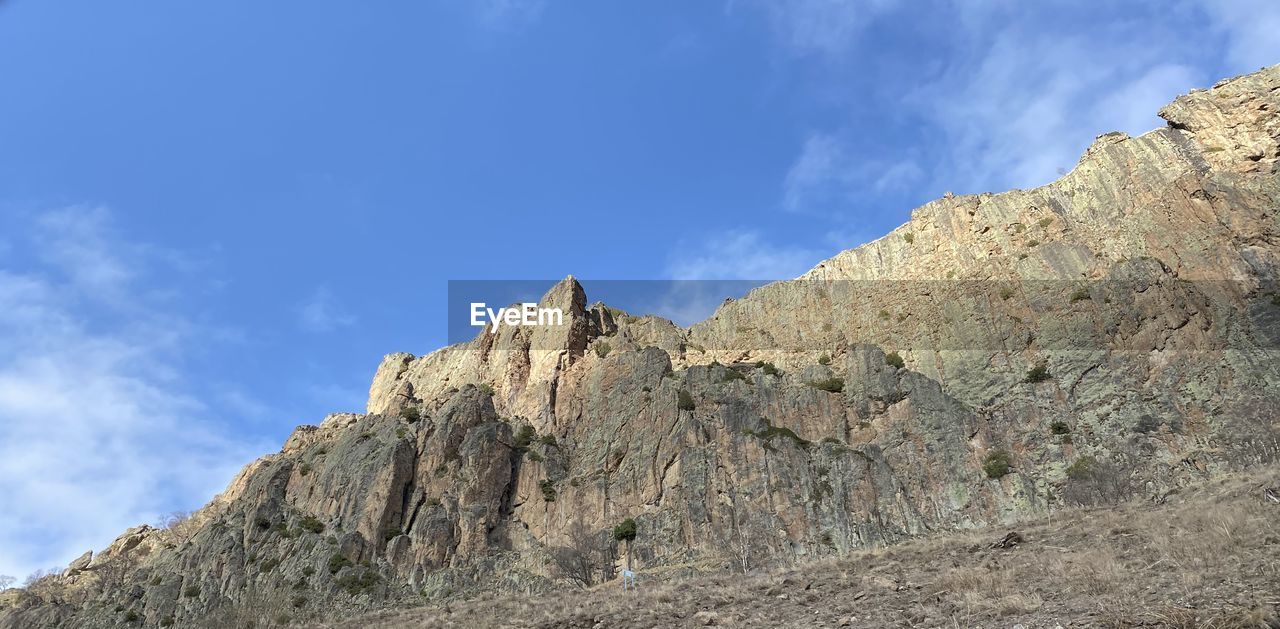 LOW ANGLE VIEW OF ROCK FORMATIONS AGAINST BLUE SKY