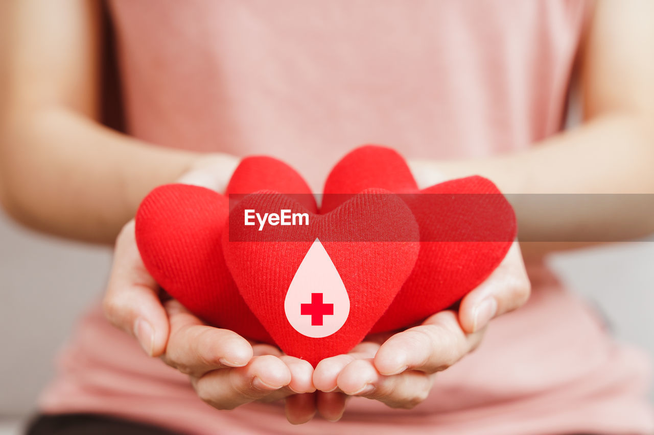 CLOSE-UP OF WOMAN HOLDING RED HEART SHAPE WITH HANDS