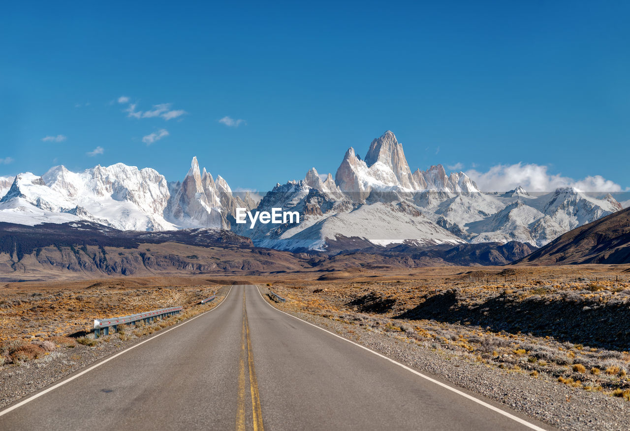 Road leading towards snowcapped mountains against sky