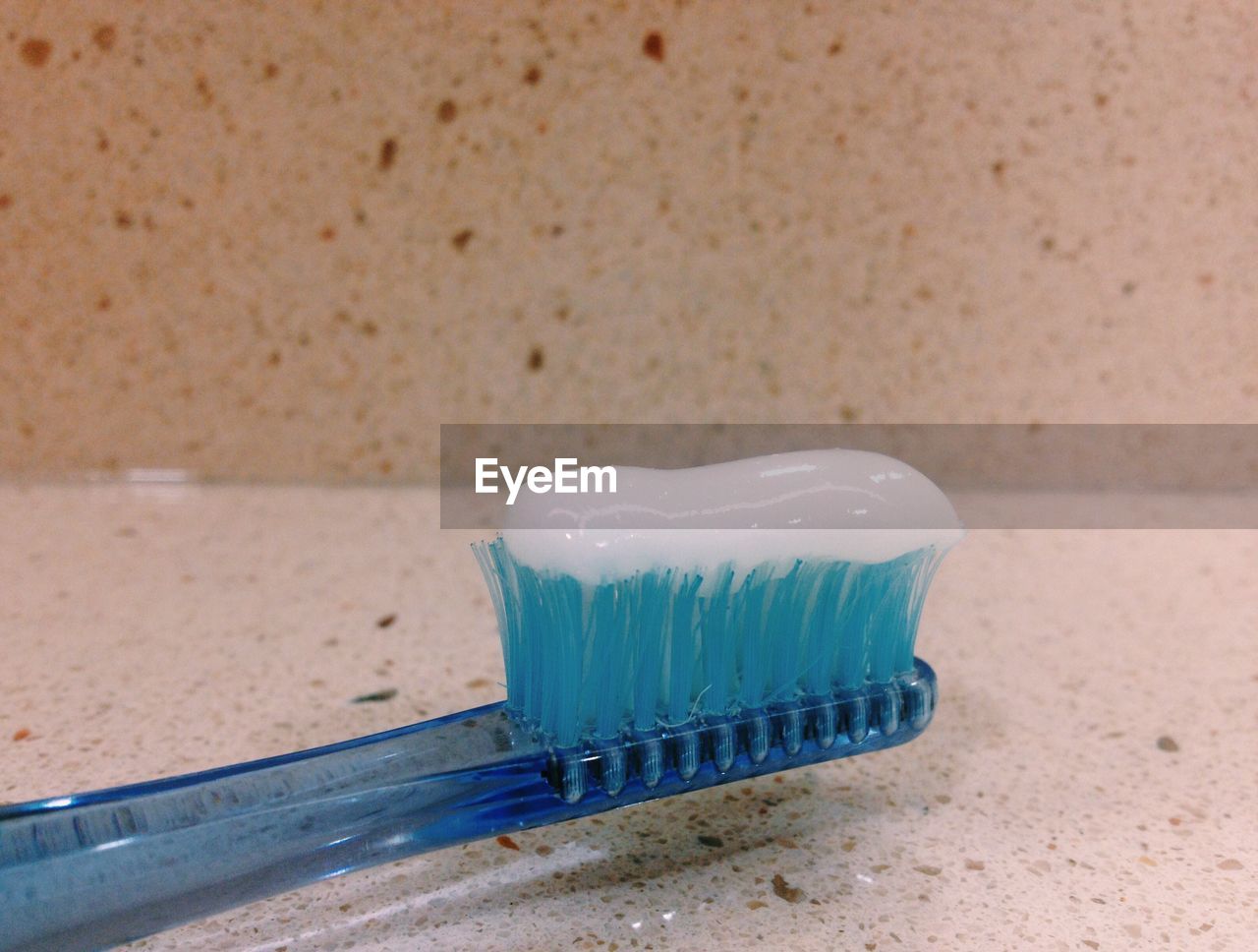 Close-up of toothpaste on blue plastic toothbrush in bathroom