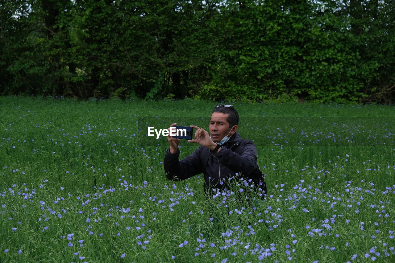 Man photographing on grassy field