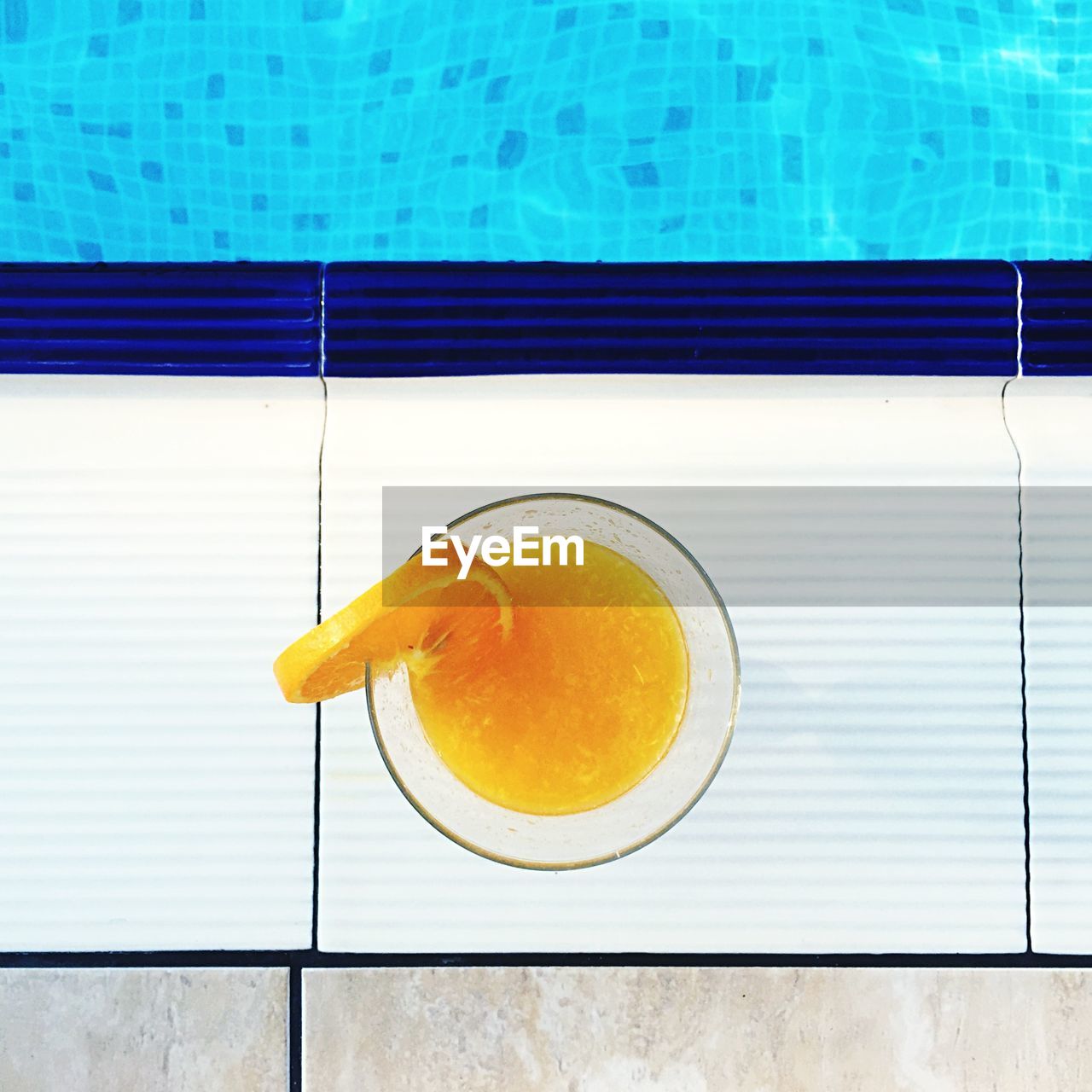 Directly above shot of orange juice glass at poolside