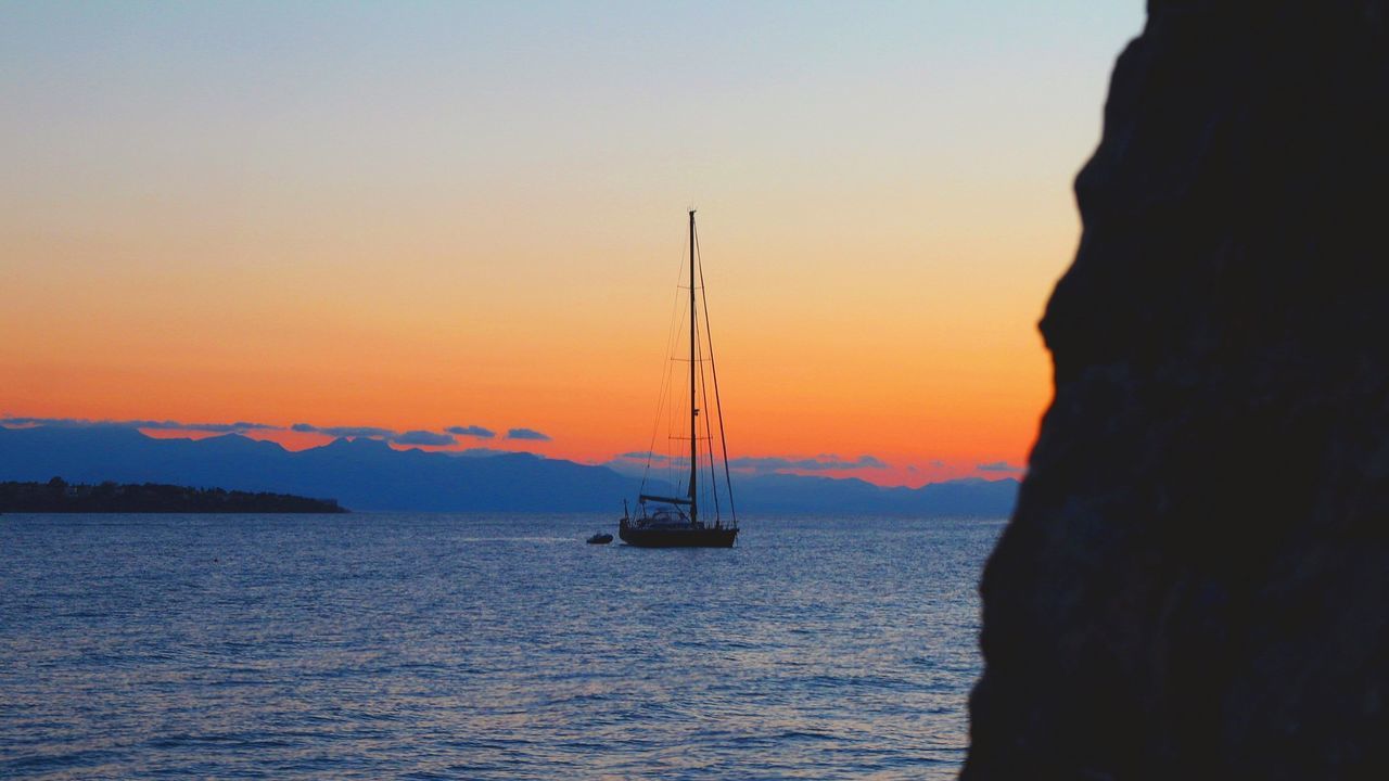 Silhouette sailboat sailing on sea against sky during sunset