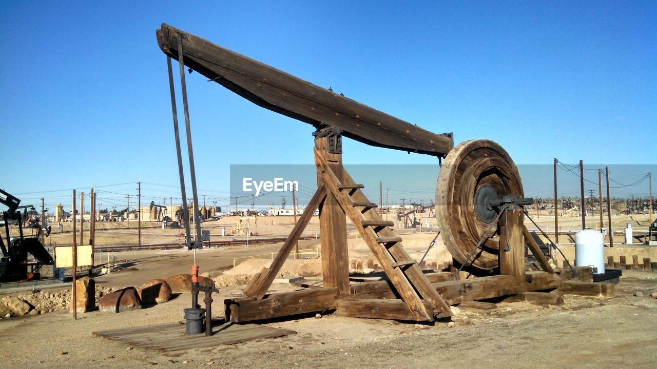 Wooden equipment at factory against clear blue sky