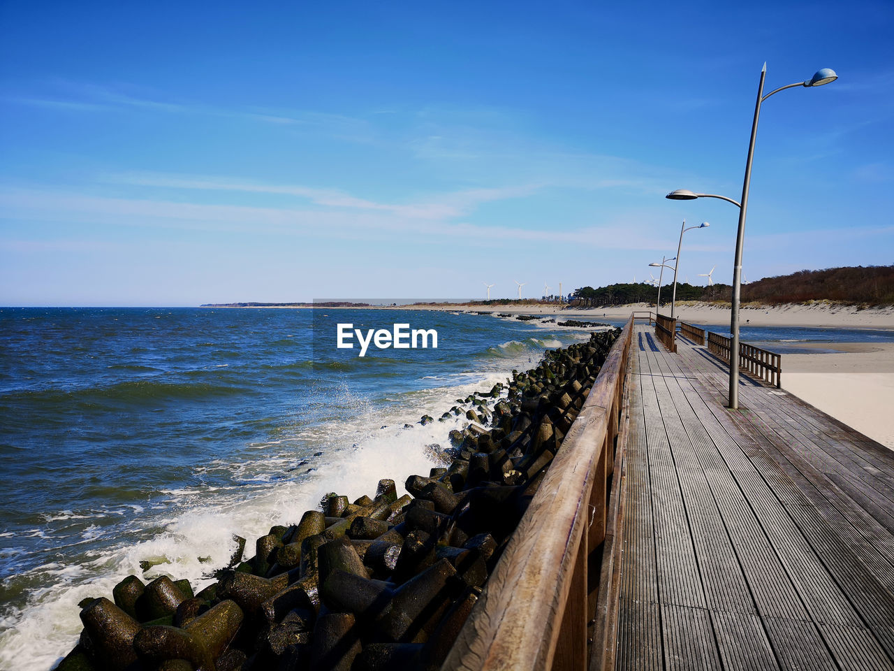 A wooden walkway by a baltic coastline with a pile of tetra-pods for sea defence/defense