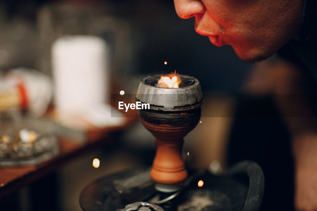 Close-up of man holding burning candle