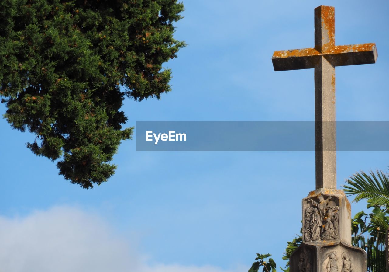 Low angle view of cross by building against sky