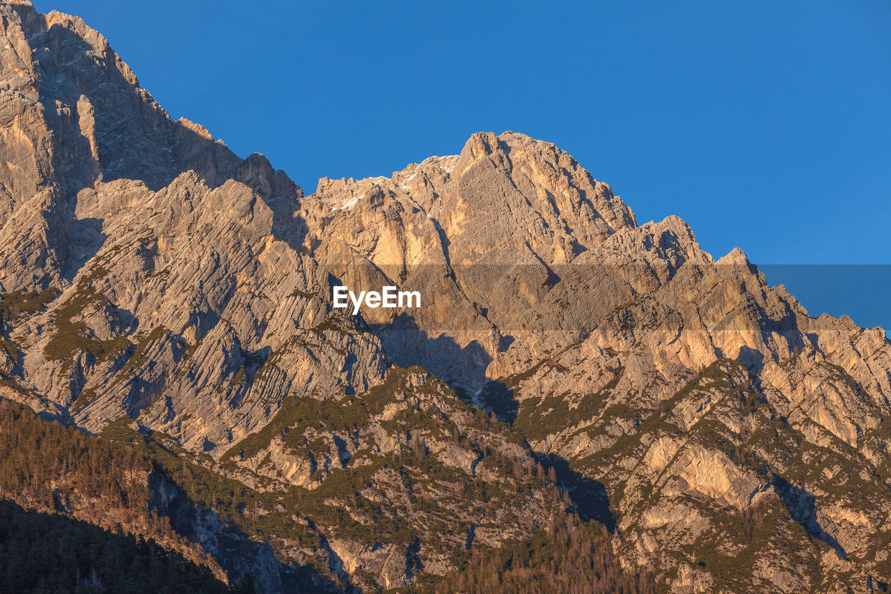 LOW ANGLE VIEW OF ROCK FORMATION AGAINST CLEAR BLUE SKY